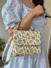 Crossbody, multi-colored floral pattern printed on a cream leather base.