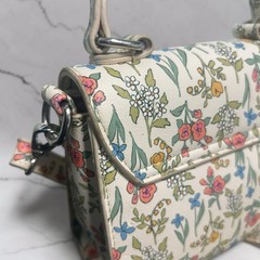 Crossbody, multi-colored floral pattern printed on a cream leather base.